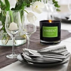 Świeca z kolekcji Ambient w czarnym eleganckim szkle z etykietą i kolorową zalewą.